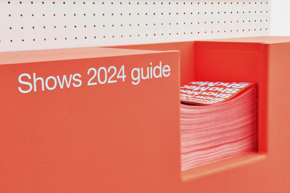 Close up view of printed show guides on an orange shelf.